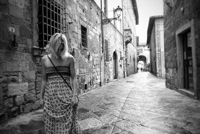 Woman standing on street amidst buildings in city