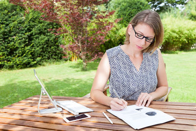 Young woman using mobile phone while sitting on grass