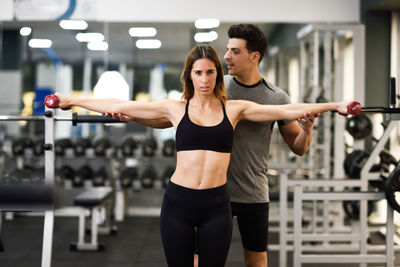 Trainer assisting woman exercising in gym