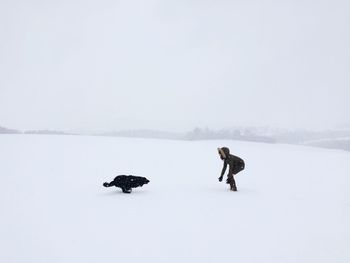 Woman and dog on snow covered landscape