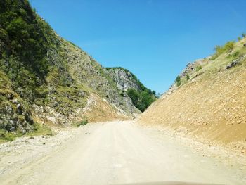 Road amidst mountains against clear blue sky