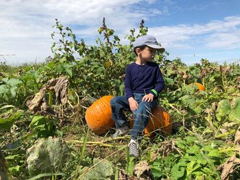 Full length of a boy with pumpkin against plants