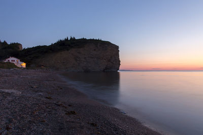 Rock formation on beach against sky during sunset