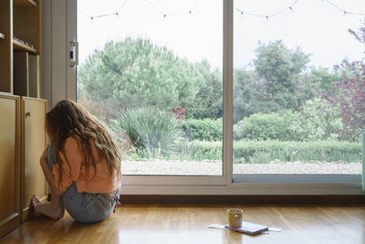 Woman sitting by window at home