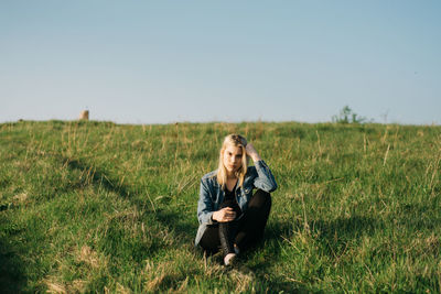 Full length of young woman sitting on field