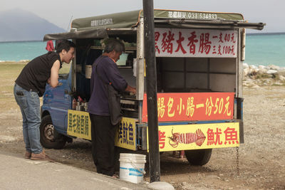 People standing on road by sign