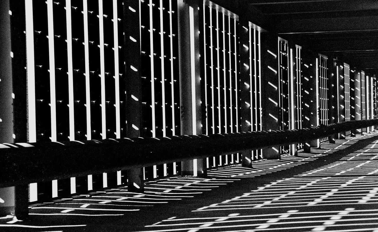 architecture, built structure, building exterior, pattern, in a row, repetition, building, shadow, railing, the way forward, sunlight, city, diminishing perspective, outdoors, day, fence, no people, metal, safety, protection