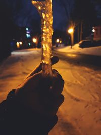 Close-up of hand holding illuminated street at night