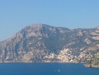 Scenic view of sea and mountains against clear blue sky