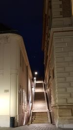 Empty alley amidst buildings at night