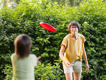 Mother and son play frisbee on grass lawn. summer vibes. family life. sports game at backyard.