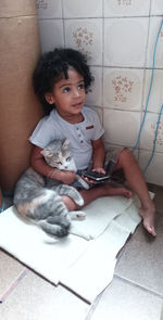Cute baby girl sitting on tiled floor at home