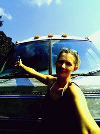 Young woman in car against sky