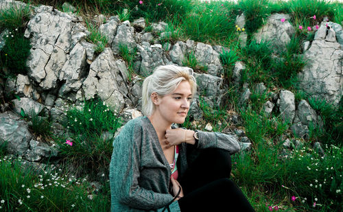 Young woman looking away while sitting on tree