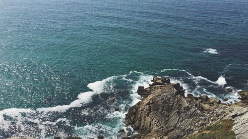 High angle view of waves breaking on cliff