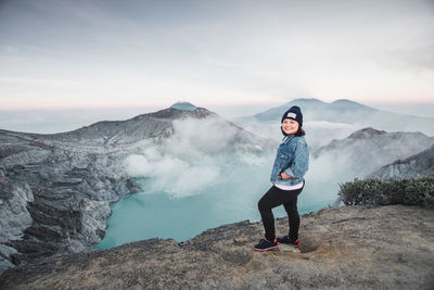 Portrait of woman standing against hot spring amidst mountains