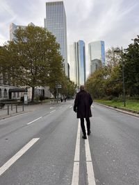 Rear view of woman walking on road against sky frankfurt skyline skyscrapers germany 