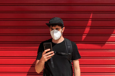 Portrait of young man standing against red wall