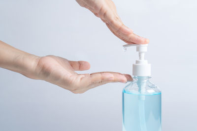 Close-up of hand holding bottle against white background