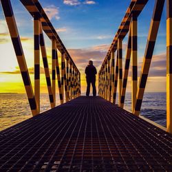 People walking on pier at sunset