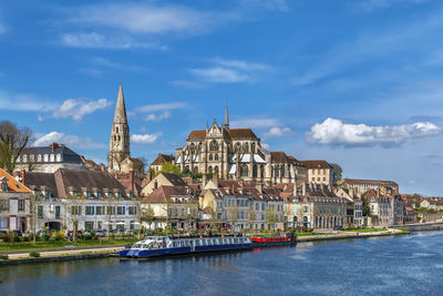 Buildings at waterfront against cloudy sky