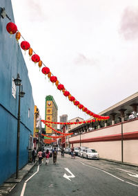 People on street amidst buildings in city against sky