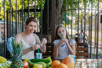 Mother and daughter drinking juice while sitting at restaurant