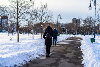 Rear view of people walking on snow during winter