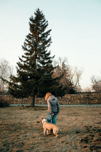 Rear view of woman walking with dog on field