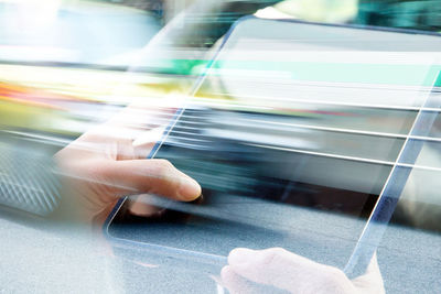 Cropped image of hand holding mobile phone in car