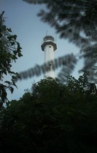 Low angle view of lighthouse by building against sky