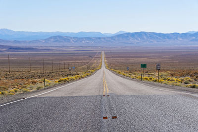 Road leading towards mountains against sky