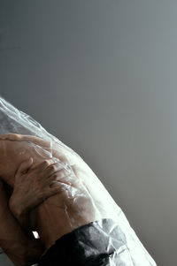 Midsection of shirtless woman wrapped in plastic against gray background