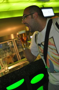 Reflection of man drinking glass on table