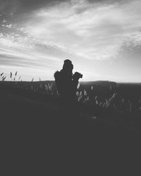 Silhouette people photographing on landscape against sky