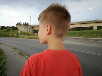 Rear view of boy standing on sidewalk