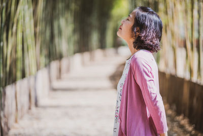 Side view of woman standing against blurred background