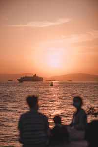 Rear view of silhouette people against sea during sunset