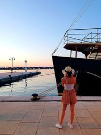 Rear view of woman standing by railing against sky