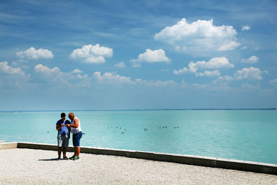 People standing by sea against sky