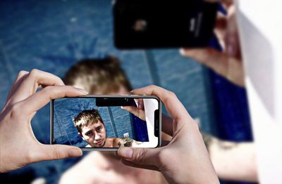 Midsection of man photographing himself with mobile phone