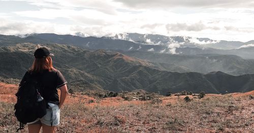 Rear view of woman looking at mountains against sky