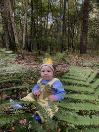 Lost child, boy sits alone in the forest frightened and sad, autumn leaves