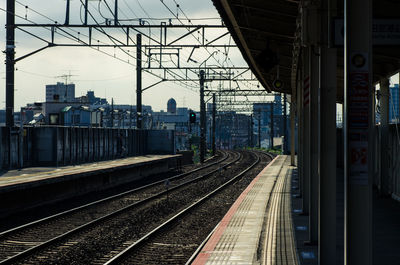 Railroad tracks in city against sky