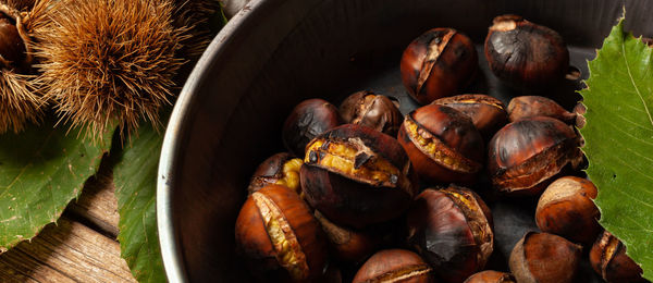 Roasted chestnuts in an iron skillet on a wooden table.