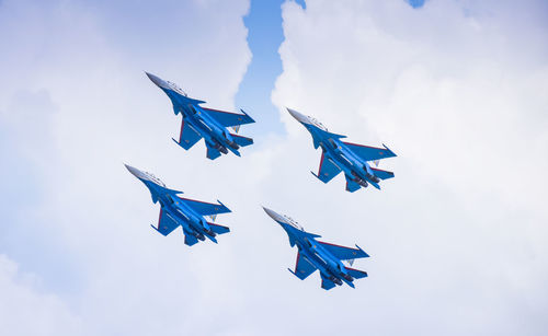 Low angle view of birds flying against blue sky