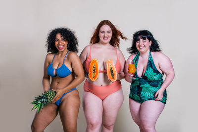 Portrait of smiling women holding fruits standing at home