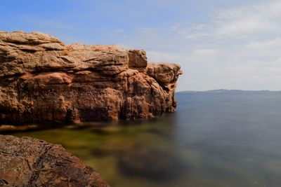 Rock formation in sea against sky