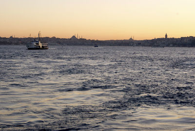 Sailboat sailing on sea against clear sky during sunset