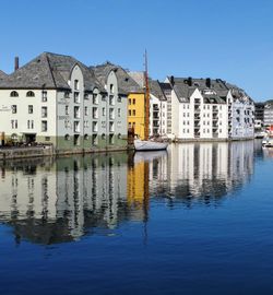 Reflection of houses in water against clear blue sky